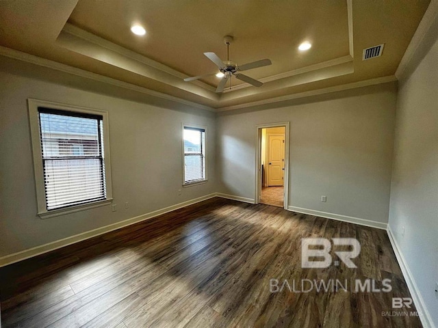 unfurnished bedroom featuring crown molding, a tray ceiling, and dark hardwood / wood-style floors