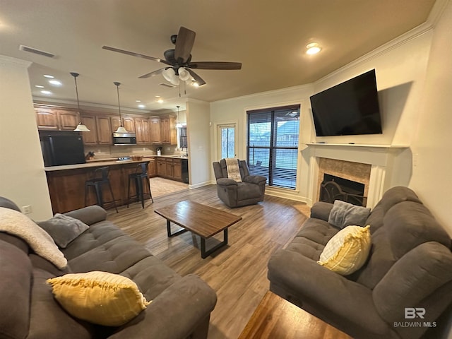 living room with crown molding, ceiling fan, and light wood-type flooring