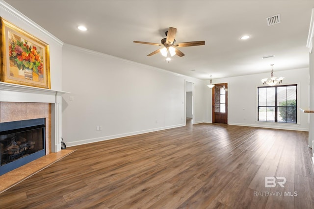 unfurnished living room with a tiled fireplace, ornamental molding, ceiling fan with notable chandelier, and dark hardwood / wood-style flooring