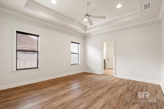 unfurnished room with crown molding, a tray ceiling, and wood-type flooring