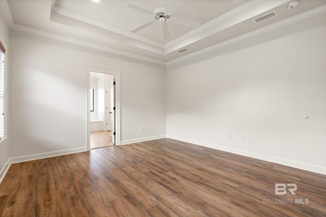 empty room featuring ornamental molding, wood-type flooring, ceiling fan, and a tray ceiling