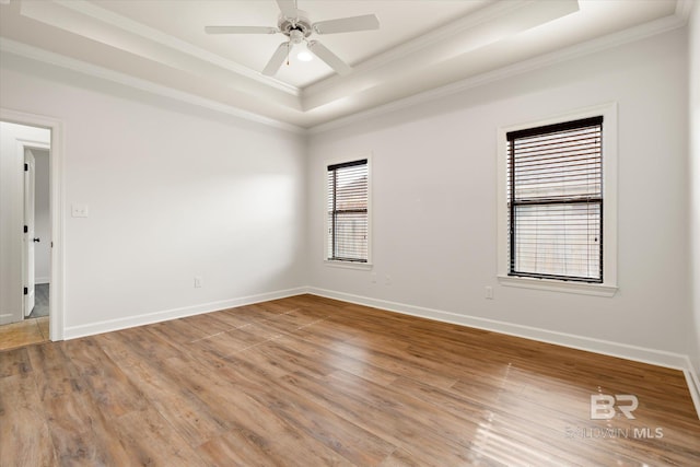 empty room with crown molding, a tray ceiling, ceiling fan, and hardwood / wood-style flooring