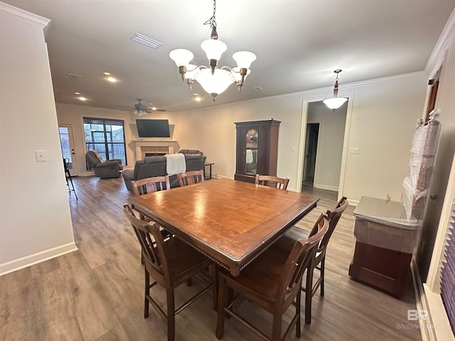 dining space with crown molding, wood-type flooring, and ceiling fan with notable chandelier