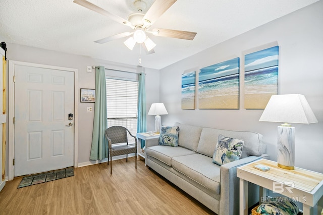 living room with ceiling fan, light hardwood / wood-style flooring, and a textured ceiling