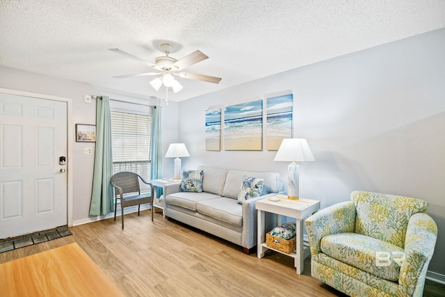 living room featuring ceiling fan, wood-type flooring, and a textured ceiling