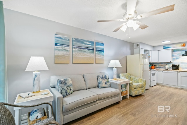 living room featuring a textured ceiling, ceiling fan, and light hardwood / wood-style flooring