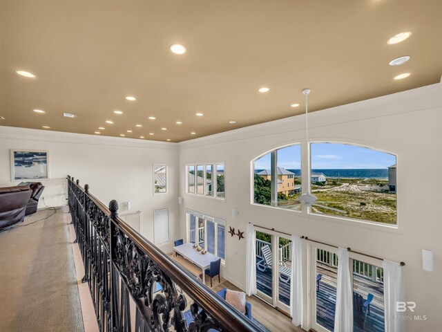 hallway with light colored carpet and a towering ceiling