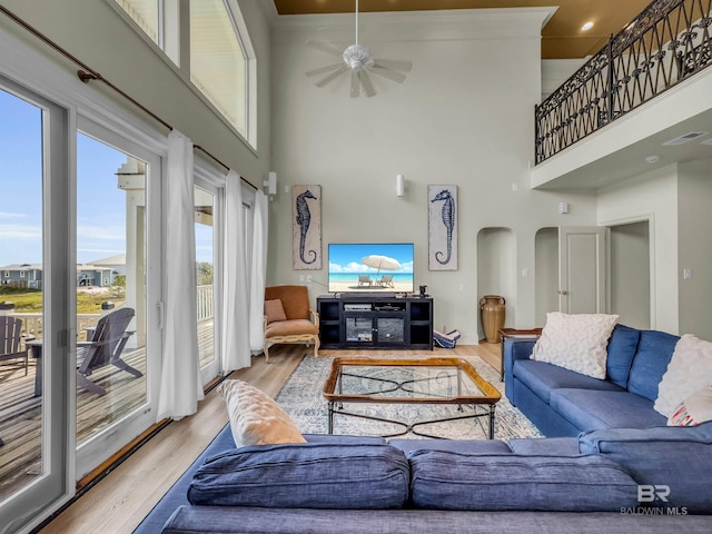 living room with ceiling fan, a towering ceiling, hardwood / wood-style floors, and plenty of natural light