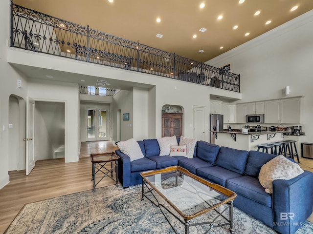 living room featuring light wood-type flooring, french doors, and a towering ceiling