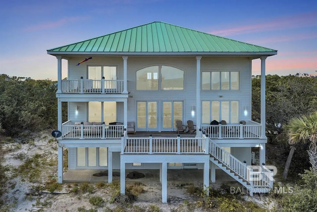 back house at dusk featuring a balcony and ceiling fan