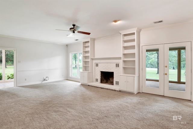 unfurnished living room featuring ceiling fan, a brick fireplace, ornamental molding, and plenty of natural light