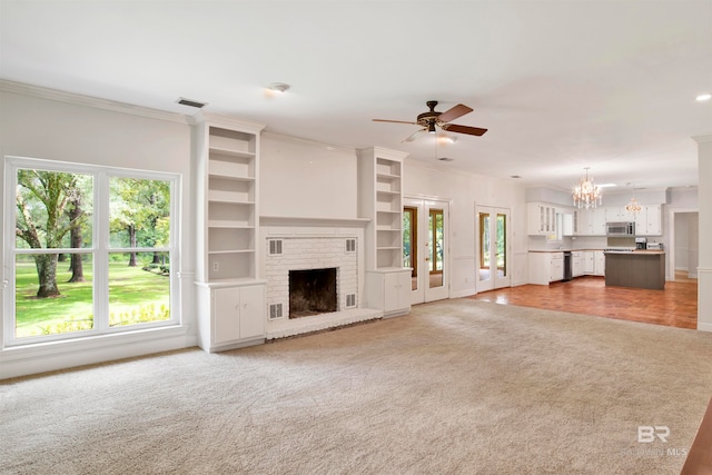 unfurnished living room with carpet floors, ceiling fan with notable chandelier, a fireplace, and crown molding