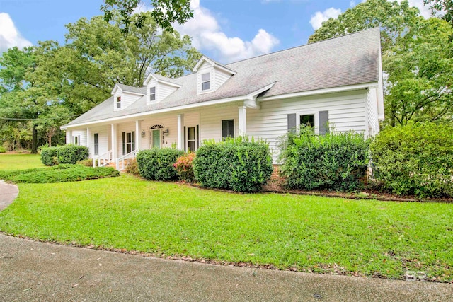 new england style home featuring a porch and a front lawn