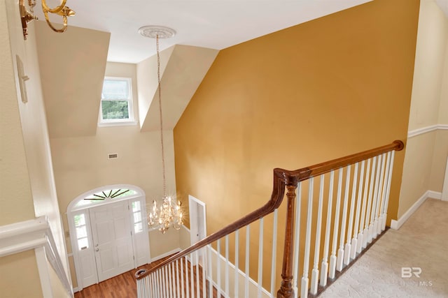 staircase with hardwood / wood-style floors and a chandelier