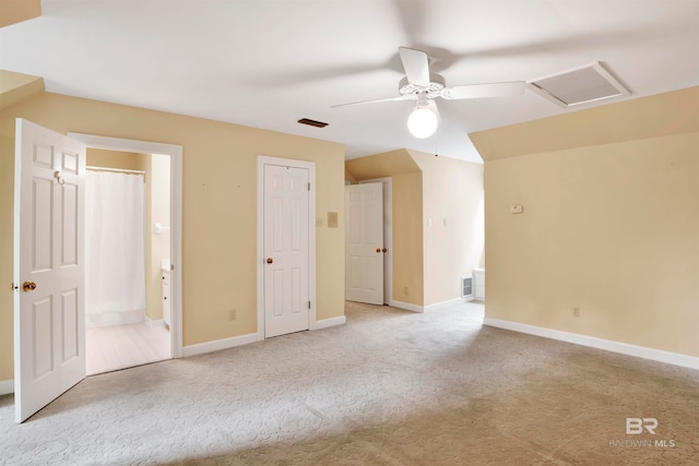 unfurnished bedroom featuring ceiling fan, light colored carpet, and ensuite bath