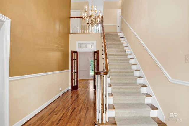 stairs with an inviting chandelier and wood-type flooring