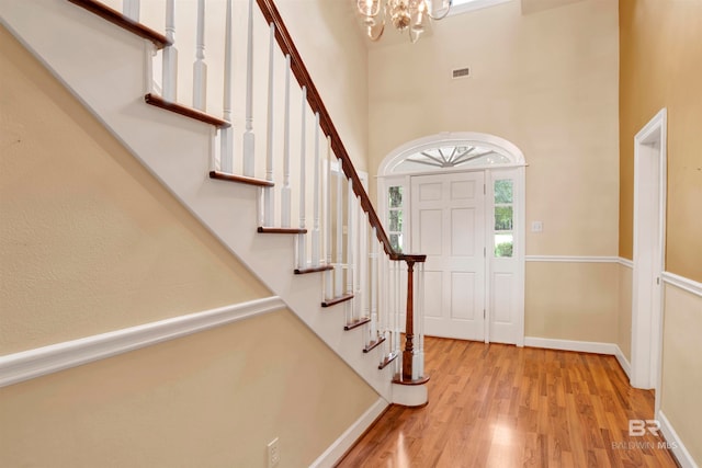 foyer entrance with a towering ceiling, light hardwood / wood-style floors, and a chandelier