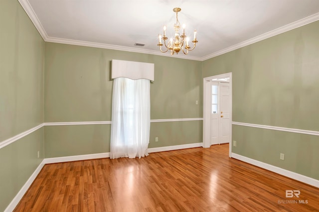 empty room with an inviting chandelier, hardwood / wood-style floors, and crown molding