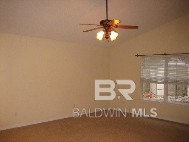 empty room featuring vaulted ceiling, a ceiling fan, and baseboards