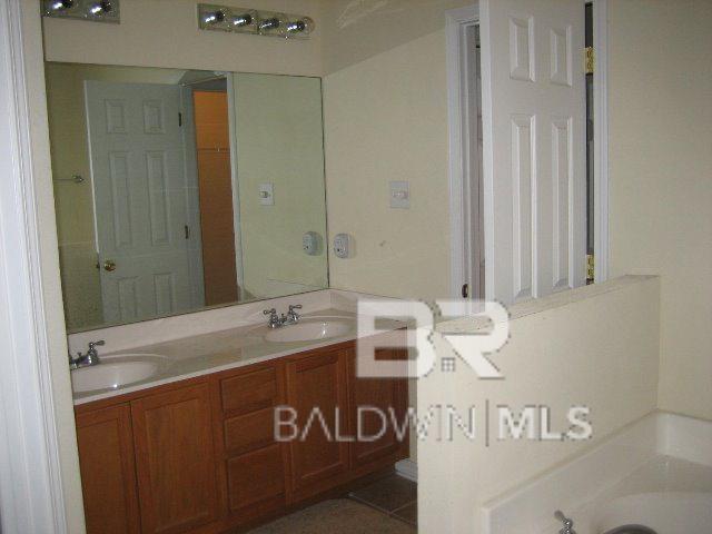 bathroom with vanity, a bath, and tile patterned floors