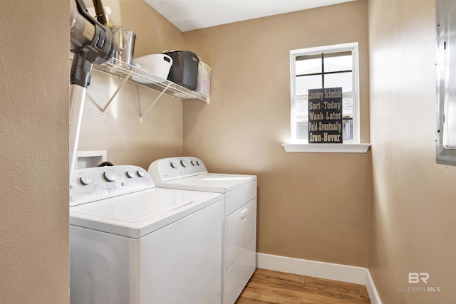 washroom featuring laundry area, washing machine and dryer, baseboards, and light wood finished floors