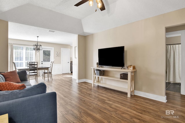 living area featuring visible vents, a ceiling fan, vaulted ceiling, a textured ceiling, and wood finished floors