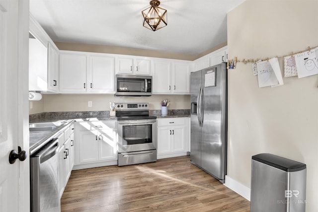 kitchen with light wood finished floors, white cabinetry, and stainless steel appliances