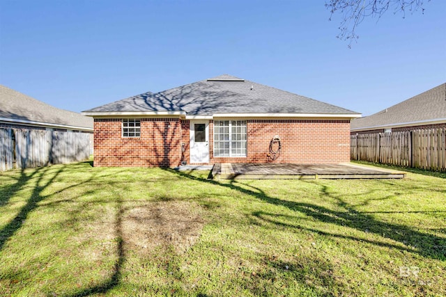 rear view of property featuring a yard, a fenced backyard, a deck, and brick siding