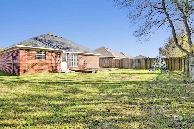 back of house featuring a patio, a fenced backyard, a yard, a playground, and brick siding