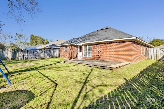 back of property with brick siding, a lawn, and a fenced backyard