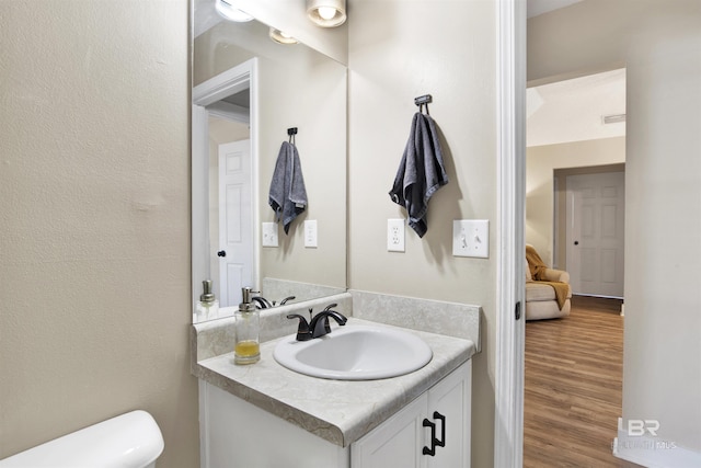 bathroom with wood finished floors, vanity, and toilet