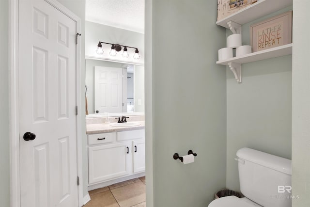 bathroom with a textured ceiling, vanity, toilet, and tile patterned floors