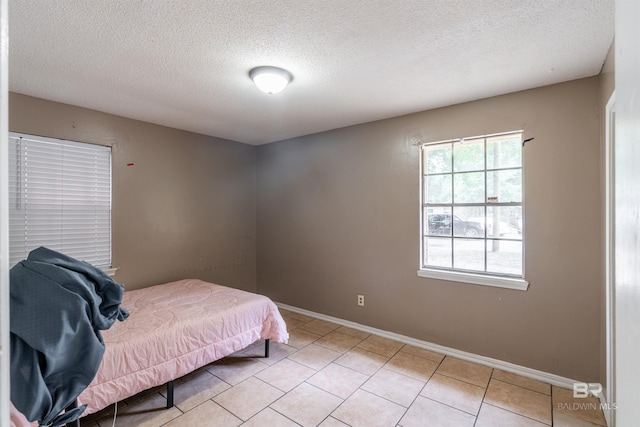 bedroom with a textured ceiling and light tile patterned floors