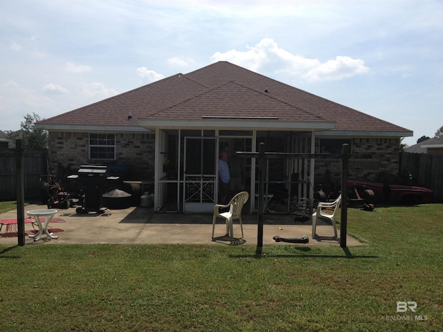 rear view of house with a lawn, a patio, fence, a sunroom, and brick siding