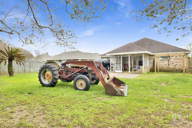 back of property with a yard, a fenced backyard, and a sunroom