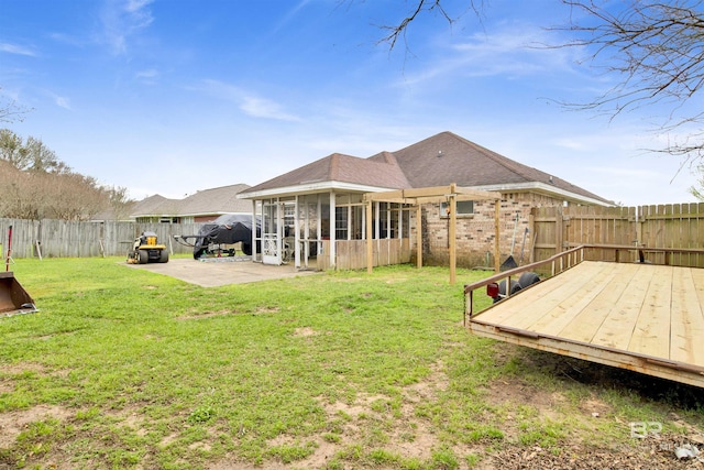 back of house with a yard, a deck, a fenced backyard, and a sunroom