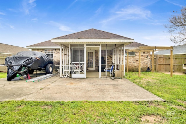 back of house featuring fence, roof with shingles, a yard, a sunroom, and a patio area