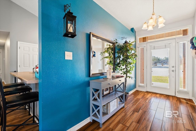 entryway with a notable chandelier, baseboards, lofted ceiling, and wood finished floors