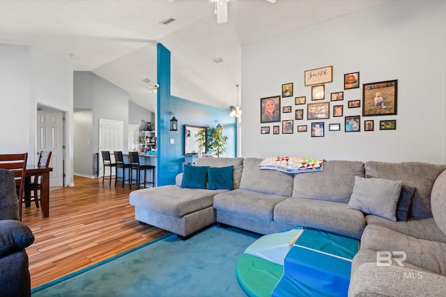 living room with visible vents, high vaulted ceiling, ceiling fan, and wood finished floors