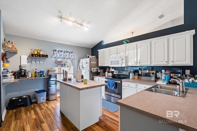 kitchen featuring white microwave, freestanding refrigerator, butcher block countertops, a sink, and stainless steel range with electric stovetop