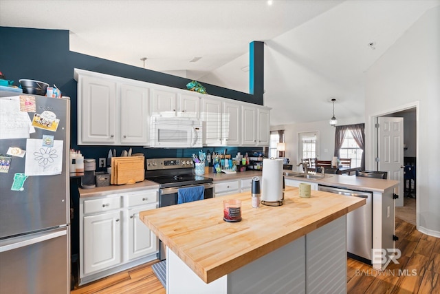 kitchen with butcher block countertops, a center island, white cabinetry, stainless steel appliances, and a peninsula