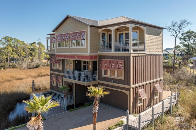 view of front of home with a garage, decorative driveway, board and batten siding, and a balcony