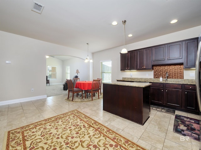 kitchen featuring a chandelier, dark brown cabinetry, decorative light fixtures, and a kitchen island