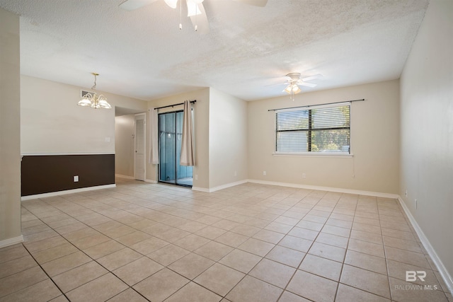 empty room with a textured ceiling, light tile patterned floors, and ceiling fan with notable chandelier