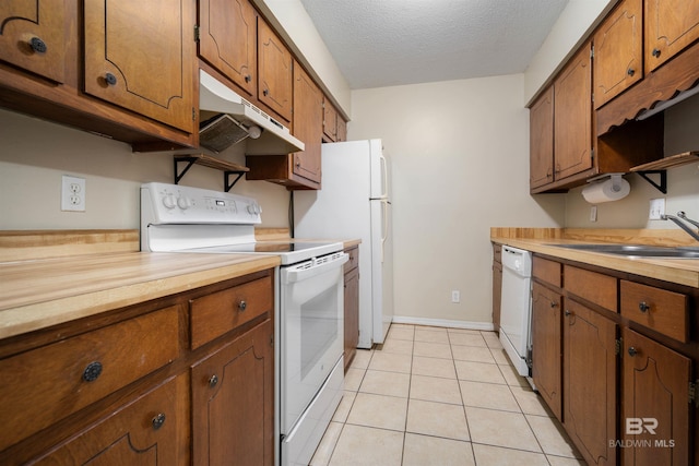 kitchen with a textured ceiling, sink, light tile patterned floors, and white appliances