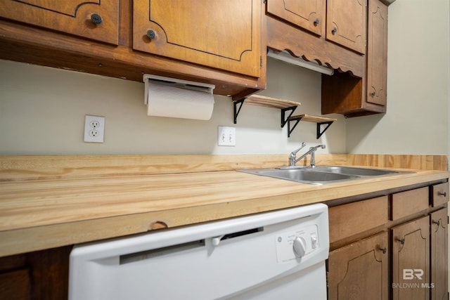 kitchen with white dishwasher, sink, and wood counters