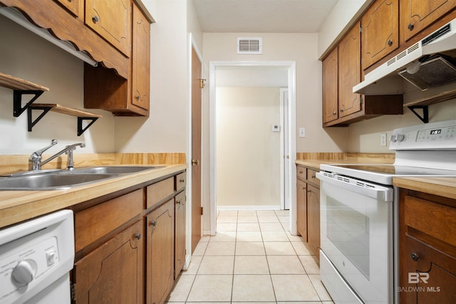 kitchen featuring light tile patterned flooring, a textured ceiling, sink, and white appliances