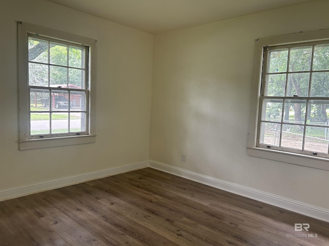 unfurnished room with dark wood-type flooring and baseboards