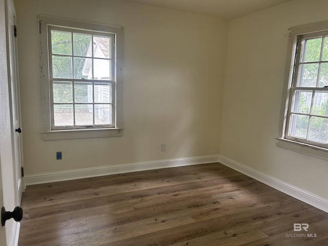 spare room with dark wood-type flooring and baseboards