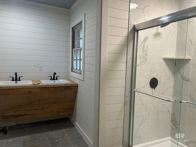 bathroom with a marble finish shower, wood walls, double vanity, and tile patterned floors